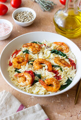 Orzo pasta with shrimp, spinach and tomatoes. Italian Cuisine. Seafood.