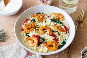 Orzo pasta with shrimp, spinach and tomatoes. Italian Cuisine. Seafood.