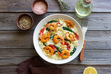 Orzo pasta with shrimp, spinach and tomatoes. Italian Cuisine. Seafood.