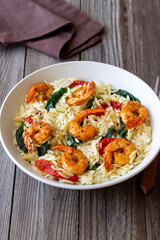 Orzo pasta with shrimp, spinach and tomatoes. Italian Cuisine. Seafood.