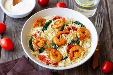 Orzo pasta with shrimp, spinach and tomatoes. Italian Cuisine. Seafood.
