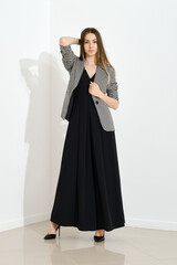 Naklejka premium Indoor portrait of trendy woman in long black dress and checkered jacket