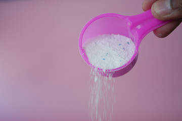 Washing powder falling from a plastic spoon 