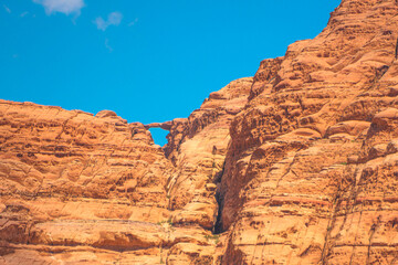 Fototapeta premium A stunning sight of the renowned Burdah rock bridge, 35 meters and spanning 20 meters, featuring the natural arch and majestic sandstone formations set against a blue sky in Jordan's Wadi Rum desert.