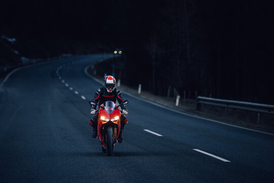 Motorcyclist leans on red racing bike in curve shadow and sunlight