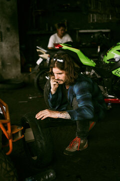 Man in moto service center, changing wheel, getting advice on phone.