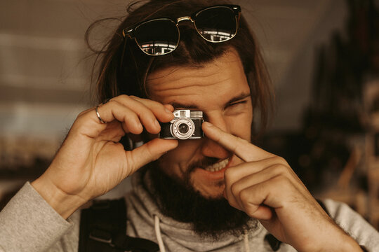 Young man photographing with tiny vintage camera - Powered by Adobe