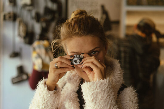 Young woman photographing with tiny vintage camera