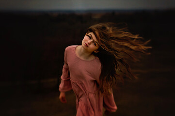 Gorgeous young girl looking into camera flipping hair pink dress