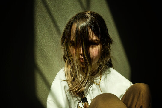 Beautiful young girl with long braids pouting in sunny room