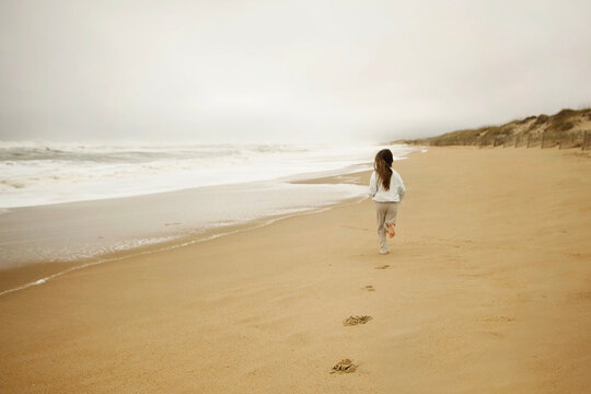 Young girl running down beach Hatters Island National Seashore
