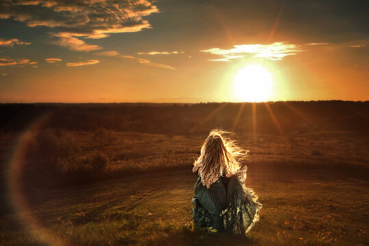 Young girl long hair flowing dress running down hill at sunset