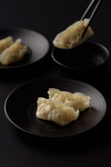 Wonton stuffed, gyoza or dumplings, Asian cultural food on black background