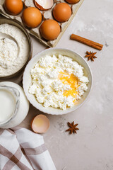 Cottage cheese in a ceramic bowl, jug of milk, flour, eggs and spices. Ingredients for cooking. Top view 