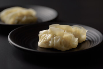 Wonton stuffed, gyoza or dumplings, Asian cultural food on black background