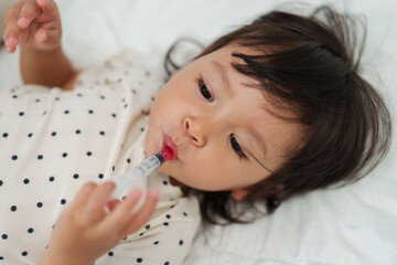 baby girl takes syrup medicine with syringe. sick toddler