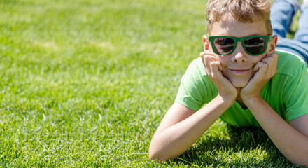 A schoolboy in sunglasses on a grassy field
