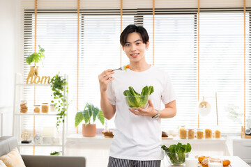 Asian man drinking milk and eating vegetable  breakfast  in kitchen at home .