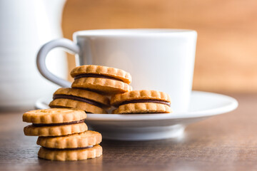 Chocolate Filled Cookies on a Wooden Table With a Cup and Pitcher in the Background