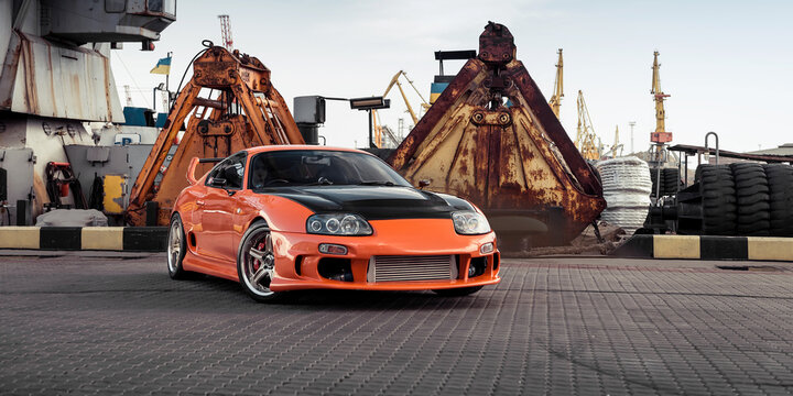 Orange Toyota Supra in sea port. Three quarter perspective view of japanese 1990s sportscar. Odesa, Ukraine - May 07 2016.