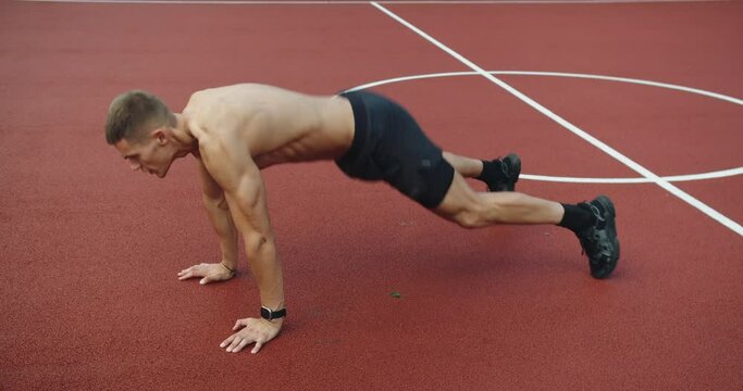 Athletic man has workout outdoors and doing burpees exercise with jump and push up at sport ground. Sports, health care, fitness routine, workout. Strength, Young man sportsman doing burpee exercise