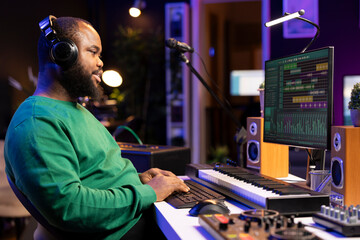 African american composer mixing and adding sounds on his recordings, listening to the final...