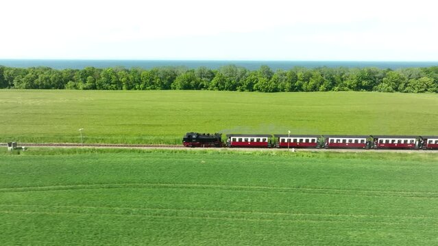Steam train travels through a meadow at the sea