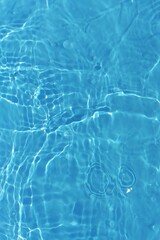 Blue water with ripples on the surface. Defocus blurred transparent blue colored clear calm water surface texture with splashes and bubbles. Water waves with shining pattern texture background.	
