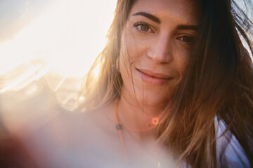 Smiling woman's close-up with soft sunlight and a hazy, warm background atmosphere