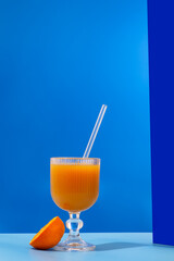 A glass of refreshing orange juice with a blue tint is placed on a table