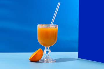A glass of refreshing orange juice with a blue tint is placed on a table