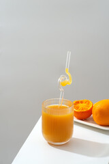 A glass of refreshing orange juice placed beside a plate of fresh oranges