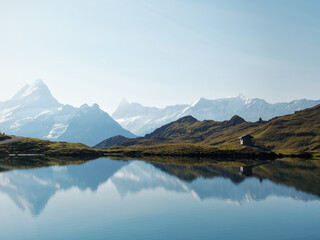 Naklejka premium Scenic Swiss lake with mirrored mountains, a serene wooden cabin on the shore