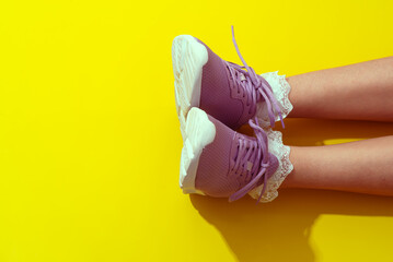 A pair of purple shoes is being showcased against a bright yellow backdrop