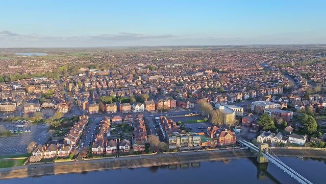 A densely built district of Nottingham, UK is shot from above. River Trent is steadily flowing and reflecting the silhouettes of houses along itself