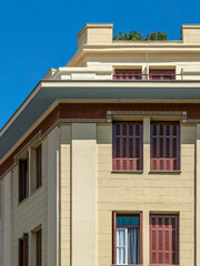 A classic design facade with brown shutters and decorative meander strips under the deep blue sky. Travel to Athens, Greece.