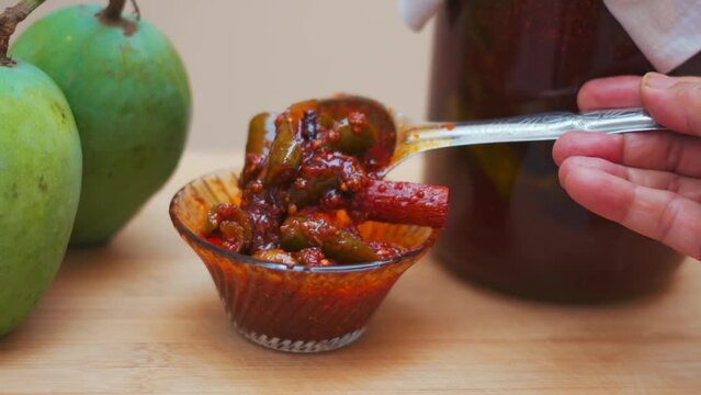 Close up shot of Mango Pickle in bowl with Raw mangoes in background in Gujarat, India. Gujarati pickle. Aam Ka Aachar. 