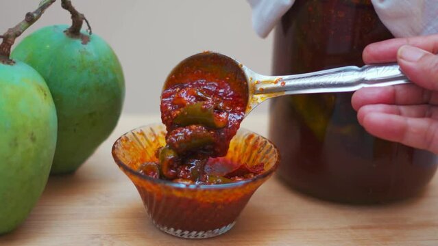 Close up shot of Mango Pickle in bowl with Raw mangoes in background in Gujarat, India. Gujarati pickle. Aam Ka Aachar. 