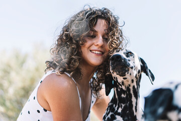 Smiling young woman with Dalmatian dog during sunny day