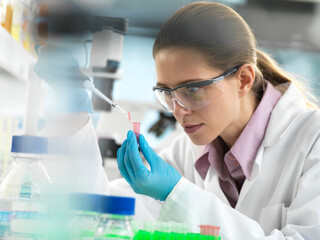 Scientist pipetting sample into a vial ready for automated analysis in the laboratory