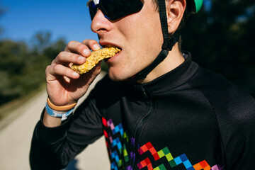 Portrait of cyclist eating a snack during a break on a sunny day