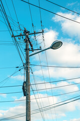 Street light with electricity utility pole and messy electrical wires against sky
