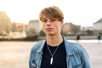 Denmark, Copenhagen, portrait of young man with earbuds in the city