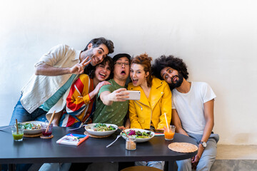 Group of friends having lunch in a restaurant taking a selfie