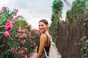 Portrait of smiling young woman with backpack strolling in a park