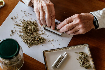 High angle view of senior man rolling weed on table at home