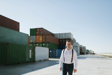 Manager in front of cargo containers on industrial site