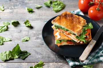 Healthy spinach, tomato and cheese sandwich on wooden table. Copy space