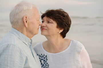 Senior couple rubbing noses in front of the sea, Liepaja, Latvia