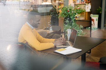 Happy man using laptop in a cafe